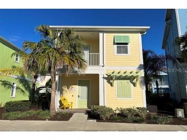 Charming yellow two-story home with lush landscaping and a welcoming front porch, and a palm tree at 3013 Latitude Ln, Kissimmee, FL 34747