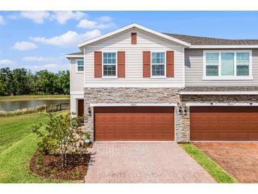 Charming townhome with stone accents, brick driveway, and a two-car garage overlooking beautiful landscaping at 4829 Cedar Bay Ter, Kissimmee, FL 34746
