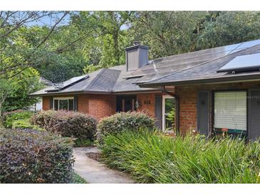 Charming brick home with a well-manicured yard and solar panels on the roof at 628 Riverpark Cir, Longwood, FL 32779