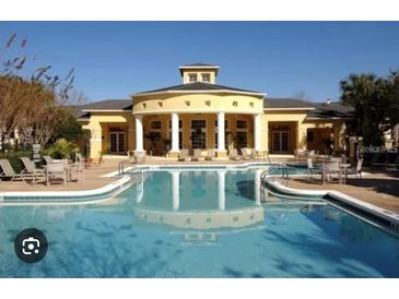 Bright yellow community clubhouse with a clear blue swimming pool and plenty of patio seating at 6450 Alcalde Ct # 106, Orlando, FL 32835