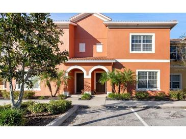 Inviting two-story townhome featuring a terra cotta exterior, arched doorways, and lush landscaping at 8941 Bismarck Palm Rd, Kissimmee, FL 34747