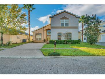 Charming two-story home with manicured lawn, lush landscaping, and concrete driveway in a sunny neighborhood at 149 Emeraldview Ave, Davenport, FL 33897