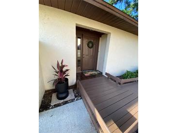 Inviting front door with welcome mat and decorative wreath, complemented by a charming wooden walkway and lush greenery at 1880 N Crystal Lake Dr # 3, Lakeland, FL 33801