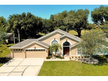Charming home featuring a well-manicured lawn, three-car garage, and an elegant entryway with arched windows at 1969 Crystal Downs Ct, Oviedo, FL 32765
