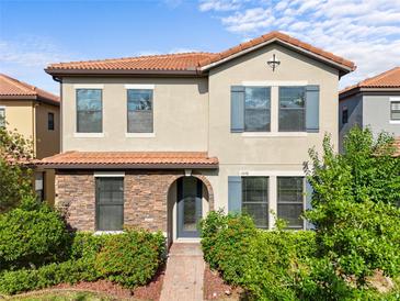 Charming two-story home featuring a stone facade, terracotta roof, and lush landscaping at 1978 Fishtail Fern Way, Ocoee, FL 34761