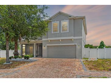 Charming two-story home features a brick driveway, attached garage, screened in porch, and a well-maintained yard at 275 Lakeshore Dr, Davenport, FL 33837
