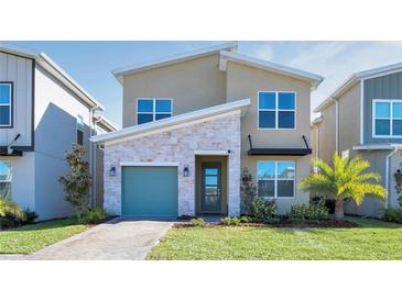 Inviting home featuring a stone accent wall, a well-manicured lawn, and a charming, colored garage door at 2821 Bookmark Dr, Kissimmee, FL 34746