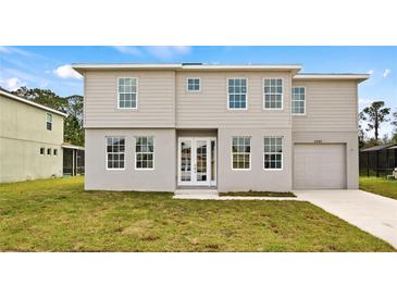 Two-story home boasts a symmetrical design with a well-manicured lawn and attached one-car garage at 4905 Pall Mall E St, Kissimmee, FL 34758
