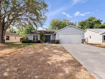 Charming single-story home features a two-car garage and well-maintained front yard with mature trees at 6042 Brookhill Cir, Orlando, FL 32810