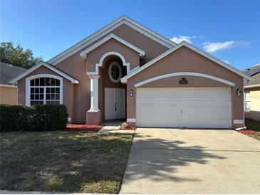 Charming single-Gathering home with a two-car garage and manicured landscaping under a bright blue sky at 6625 Cherry Grove Cir, Orlando, FL 32809