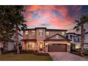Charming two-story home with well-manicured lawn, stone accents and two-car garage, set against a colorful sunset sky at 8180 Valhalla Ter, Reunion, FL 34747