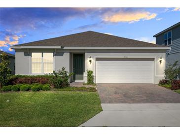 Charming single-story home featuring a manicured lawn, neutral paint, and a two-car garage at 17335 Million Lakes Ct, Clermont, FL 34714