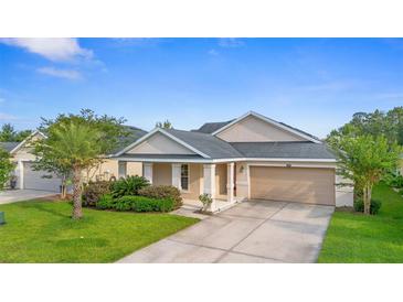 Charming single-story home featuring a covered porch, two car garage, and well-manicured landscaping at 305 Grande Lake Dr, Daytona Beach, FL 32124