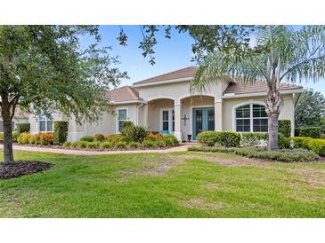 Charming, landscaped front yard featuring a lush lawn, colorful plants, and mature trees accentuating this inviting home at 31754 Red Tail Blvd, Sorrento, FL 32776