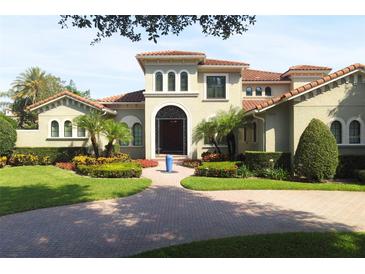 Elegant Mediterranean-style home featuring a tile roof, lush landscaping, and a circular driveway with a front water feature at 11013 Ullswater Ln, Windermere, FL 34786