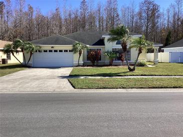 Charming single-story home with a well-manicured lawn, palm trees, and a two-car garage at 116 Blackwater Ct, Kissimmee, FL 34743
