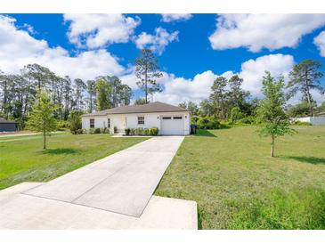 Charming single-story home with a well-manicured lawn, a long driveway, and an attached garage at 2498 Iris Rd, Deland, FL 32724