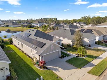 Aerial view of home with solar panels, manicured lawn and landscaping, and a two car garage at 2941 Marlberry Ln, Clermont, FL 34714