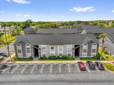 Condominium building featuring a well-kept gray exterior and ample parking with mature landscaping at 4160 Pershing Pointe Pl # 4, Orlando, FL 32822