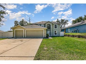 Inviting two story home featuring an attached three car garage and a well manicured lawn at 9532 Water Fern Cir, Clermont, FL 34711