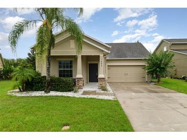 Charming single-Gathering home featuring a well-manicured lawn, two-car garage, and tropical landscaping at 1089 Seburn Rd, Apopka, FL 32703