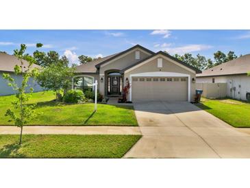 Charming single-story home featuring a well-manicured lawn and a two-car garage at 228 Bergamot Loop, Davenport, FL 33837