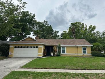 Charming yellow single-Gathering home with a well-maintained lawn and a two car garage at 243 Country Landing Blvd, Apopka, FL 32703