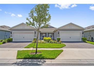 Charming home featuring a well-manicured lawn, paver driveway, two-car garage and a cozy front porch at 2960 Cherry Blossom Loop, St Cloud, FL 34771