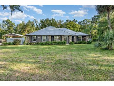 Inviting single-story home featuring a well-manicured lawn, stone accents, and a durable metal roof at 433 Tangerine Ave, Lake Helen, FL 32744