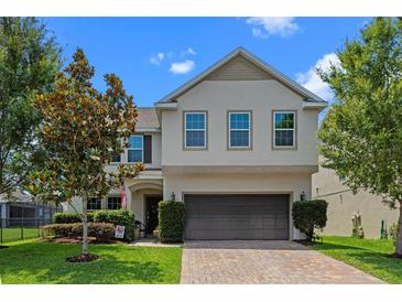 Two-story home with a well-manicured lawn and a brick driveway leading to a two-car garage at 646 Marsh Reed Dr, Winter Garden, FL 34787