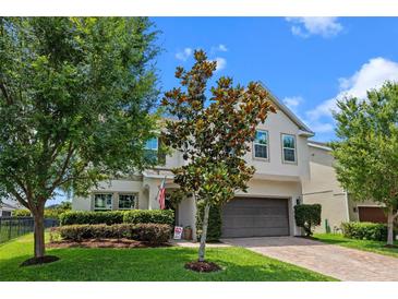 This two-story home features a well-manicured lawn, brick driveway, and an inviting front porch at 646 Marsh Reed Dr, Winter Garden, FL 34787