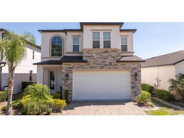 Two-story home featuring stone accents, attached two car garage and a brick paver driveway at 1311 Arisha Dr, Kissimmee, FL 34746