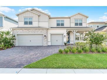 Charming two-story home featuring a three-car garage, brick driveway, and a well-manicured lawn at 13758 Tybee Beach Ln, Orlando, FL 32827