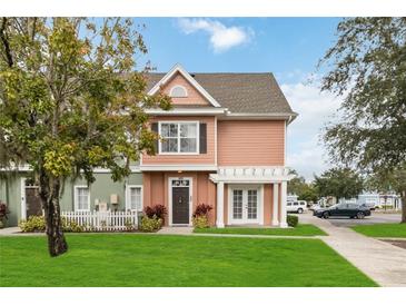 Charming two-story townhome featuring a landscaped front yard with healthy green grass and a welcoming entrance and walkway at 2204 San Vittorino Cir # 102, Kissimmee, FL 34741