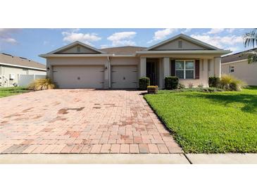 Charming single-story home with a brick driveway, well-manicured lawn, and a welcoming front entrance at 2249 Palmetum Loop, Apopka, FL 32712
