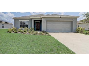 Charming single-story home featuring a well-manicured lawn and a two-car garage at 392 Citrine Loop, Kissimmee, FL 34758