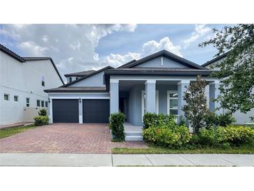 Charming two-story home featuring a brick driveway, lush landscaping, and a covered entryway with elegant columns at 9917 Summerlake Groves St, Winter Garden, FL 34787