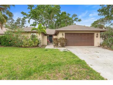 Inviting single-story home with a lush green lawn, mature trees, and a spacious driveway at 11 Huntley Ct, Haines City, FL 33844