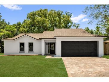 Charming single-story home features a lush lawn, modern design, and a spacious two-car garage at 1301 Paradise Ln, Winter Park, FL 32792
