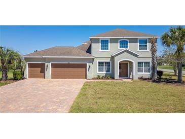 Charming two-story home featuring a three-car garage, lush lawn, and manicured landscaping at 14537 San Lorenzo Dr, Orlando, FL 32820