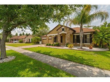 Charming single Gathering home featuring stone accents, manicured lawn, and mature trees at 9852 Caroline Park Dr, Orlando, FL 32832
