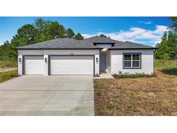 Charming single-story home with a three-car garage, neutral paint, and well-manicured lawn at 12885 Sw 43, Ocala, FL 34473