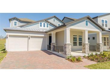 Charming home featuring a spacious two-car garage and inviting covered front porch with stone accents at 16103 Silver Brook Way, Winter Garden, FL 34787