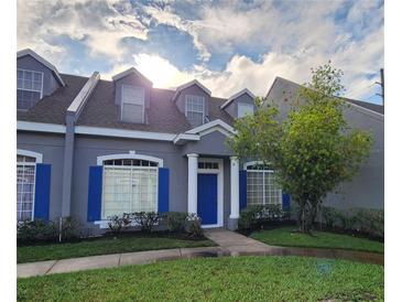 Charming townhouse with blue shutters, a blue front door, and a well-manicured lawn at 2157 Island Walk Dr, Orlando, FL 32824