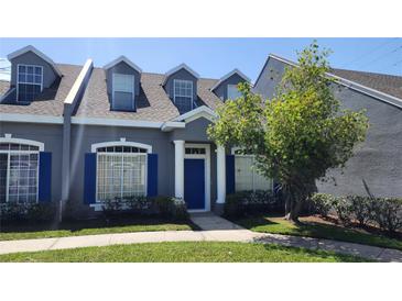 Charming two-story townhome with blue shutters, a well-maintained lawn, and mature tree at 2157 Island Walk Dr, Orlando, FL 32824