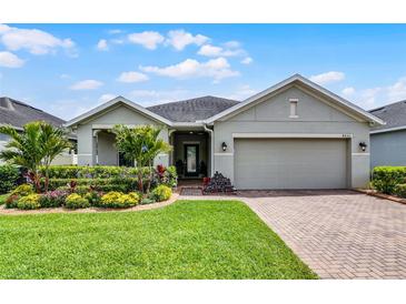 Charming single-story home with lush landscaping, manicured lawn, and a brick driveway at 4051 Prairie Reserve Blvd, Orlando, FL 32824