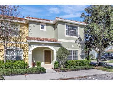 Charming two-story townhome with a well-maintained lawn, neat shrubbery, and a decorative tile roof at 8919 Bismarck Palm Rd, Kissimmee, FL 34747