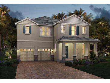 Two-story home featuring a brick paver driveway, a two-car garage, and lush landscaping at 11057 Hollow Bay Dr, Winter Garden, FL 34787