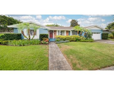 Charming blue home with well-manicured front yard, lush landscaping, and inviting brick walkway at 1516 Arthur St, Orlando, FL 32804