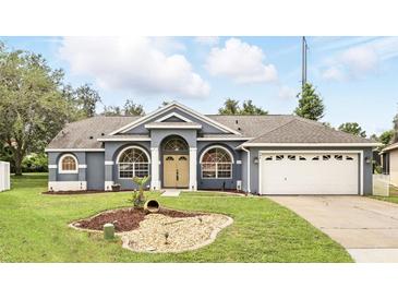 Charming single-story home with a well-manicured lawn, beautiful arched windows, and an attached two-car garage at 394 Hickory Springs Pl, Debary, FL 32713